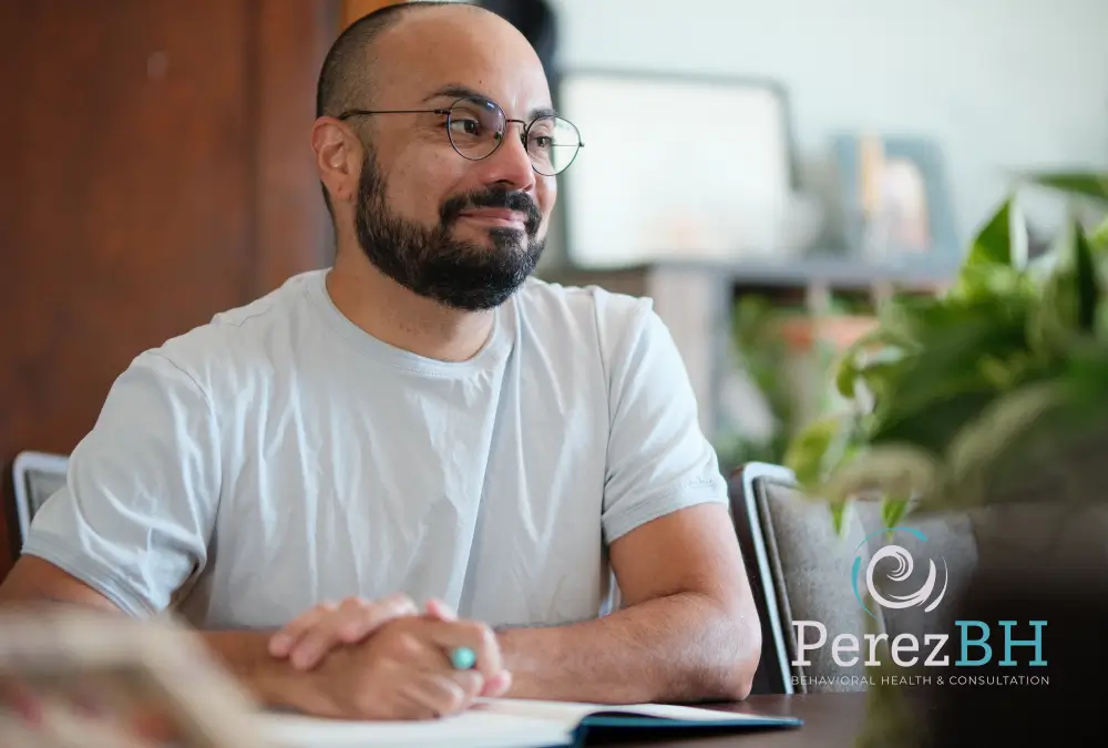 Man sitting at table, smiling, with notepad.